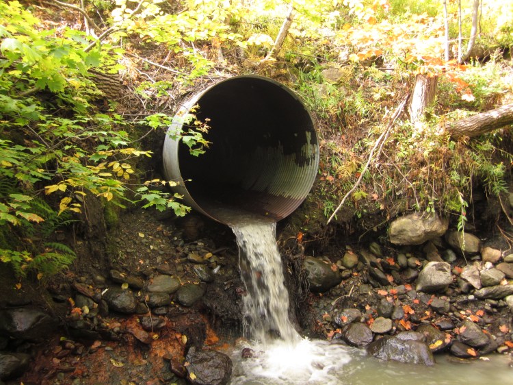 Michael indicated that metal culverts, such as this, are poorly suited to the Mattole region: they have difficulty handling the large amounts of rain that fall every winter and allow too much sediment to flow downhill. He recommends the use of rock fords instead. Culvert With a Drop by Sickter6. CC BY-SA 3.0